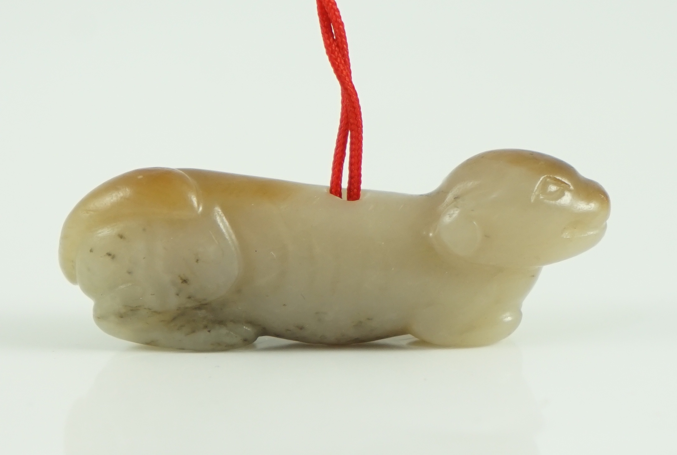 A Chinese pale grey and russet jade figure of a hound, probably Song dynasty, 4.9 cm long